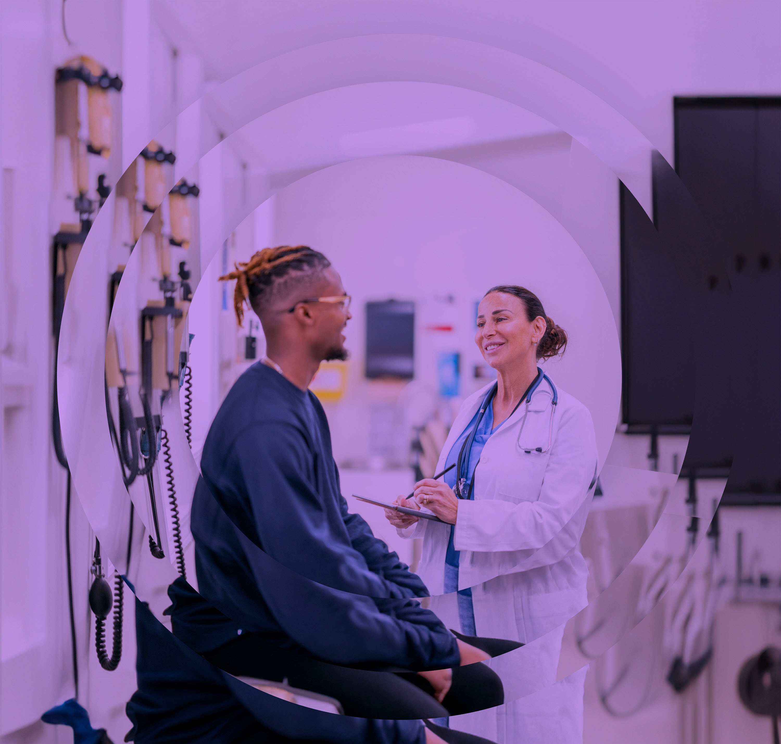 Un homme souriant avec des lunettes parle à une médecin qui prend des notes, dans un contexte médical.
