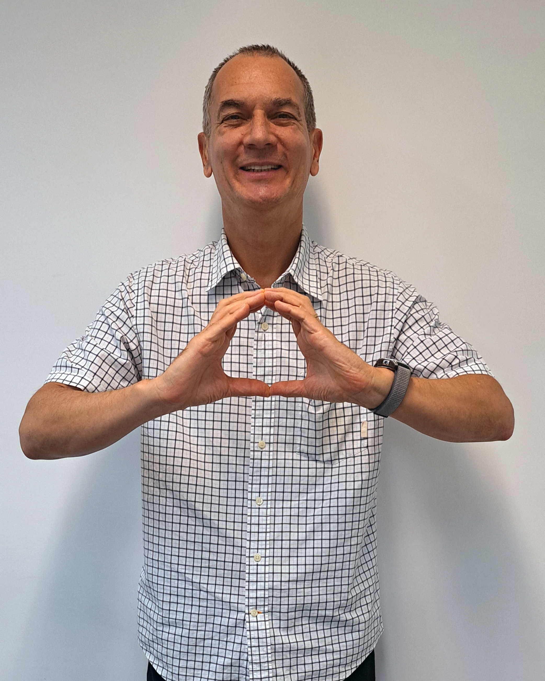 Homme souriant formant le logo OneHealth avec les mains.